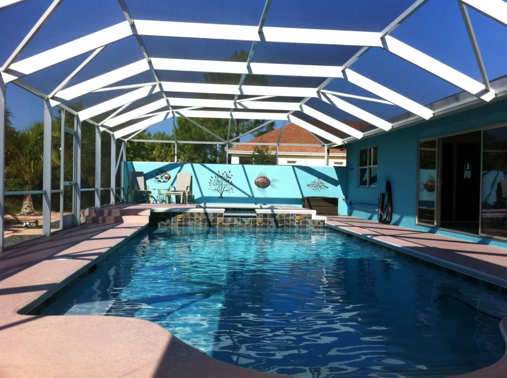 Large screened pool enclosure with white aluminum frame and gable roof protecting pool and spa area in Florida.
