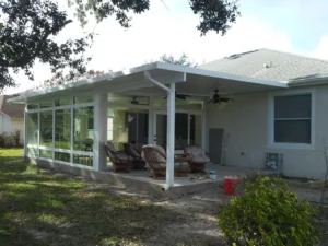 New flat roof sunroom addition by All Star Sunrooms with full-glass walls and protected outdoor sitting area in Florida.