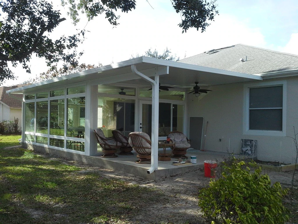 New flat roof sunroom addition by All Star Sunrooms with full-glass walls and protected outdoor sitting area in Florida.