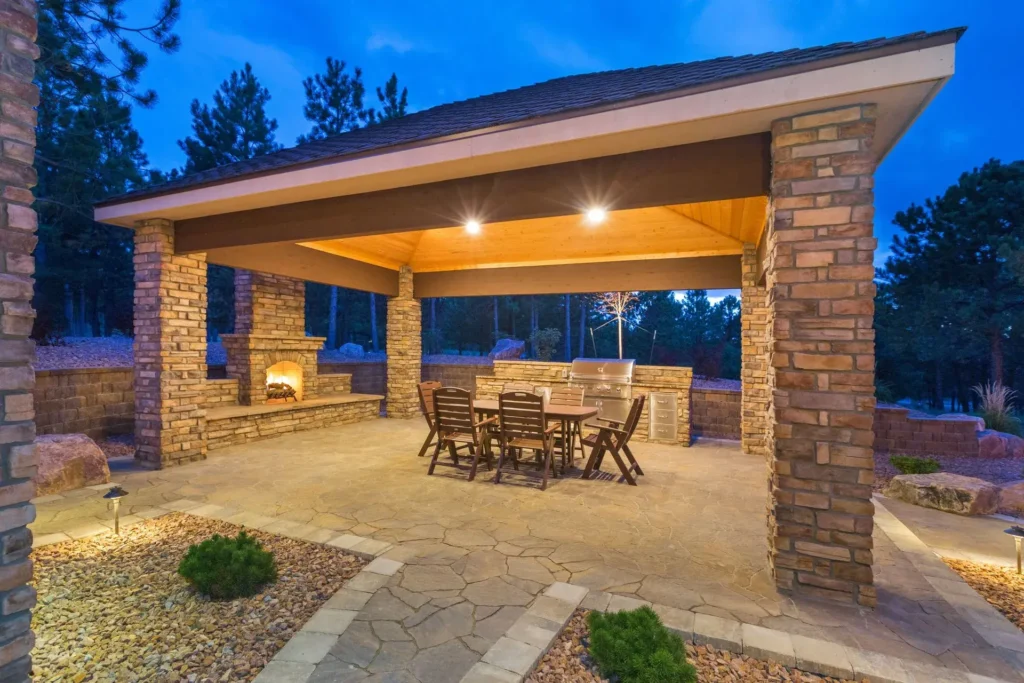 Luxury outdoor pavilion with stone columns, fireplace, built-in grill, and dining area installed by All Star Sunrooms.