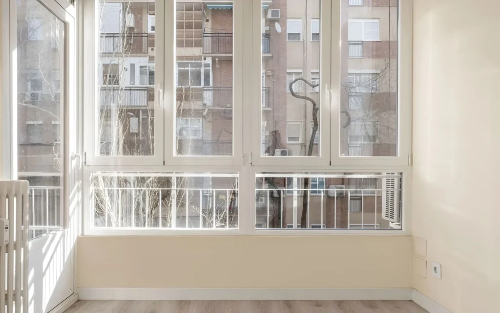 Urban balcony or terrace enclosure with large white PVC windows providing insulation and extra living space installed by All Star Sunrooms.