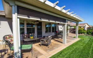 Custom outdoor living area with wood framed patio cover, stone fireplace, and built-in grill installed by All Star Sunrooms.