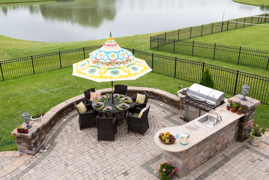 Custom outdoor kitchen and paver patio with dining area and wrought iron fence installed by All Star Sunrooms.