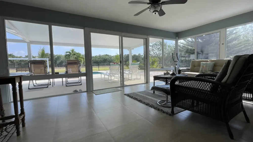 Interior view of new sunroom addition by All Star Sunrooms with large sliding glass walls overlooking a screened pool.